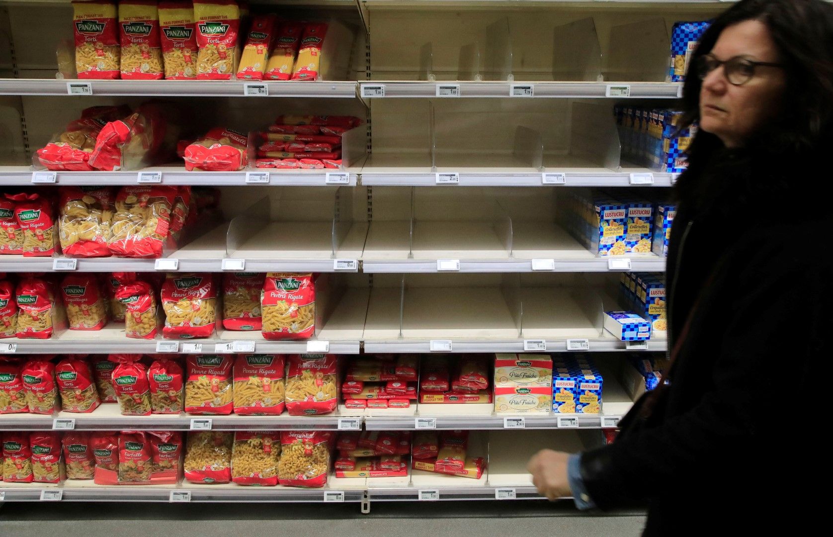 Жена минава сред опразнени заради коронавируса рафтове в супермаркет в Париж