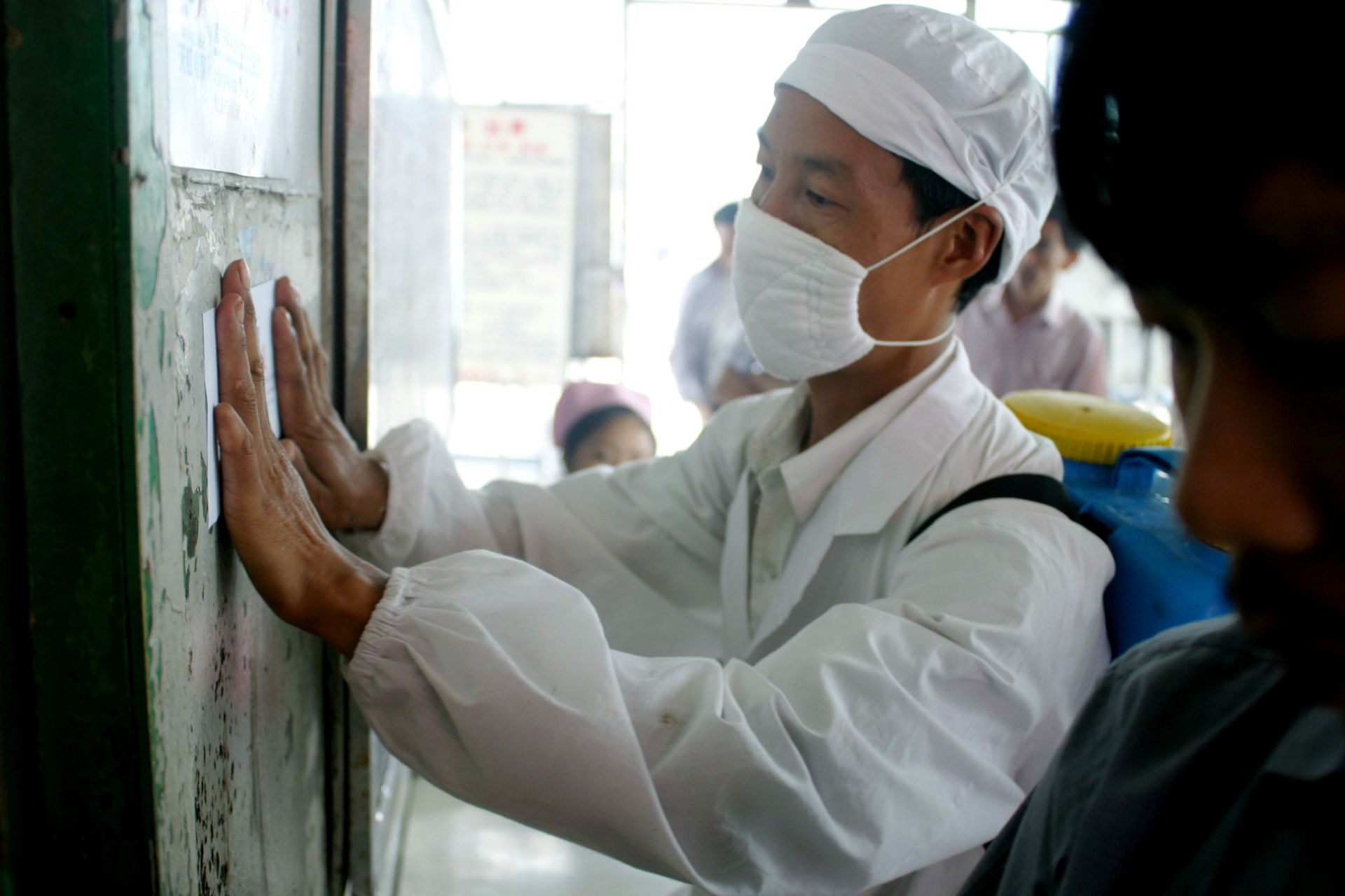  7 юни 2003 г. в Ушан, Китай: Медицински работник публикува съобщение за SARS на контролно-пропускателен пункт, където пътници се качват на лодка до Ичанг в пристанището на Ушан