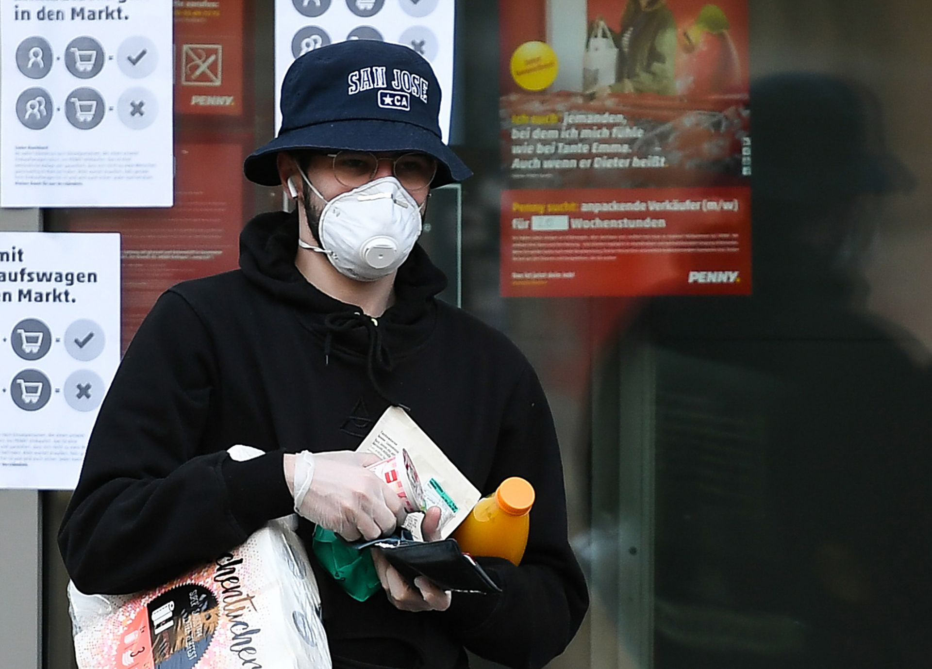Мъж, носещ маска за лице и ръкавици, напуска супермаркет във Франкфурт Мъж, носещ маска за лице и ръкавици, напуска супермаркет във Франкфурт