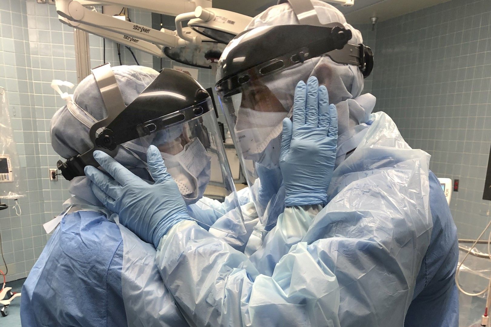 Медицински работници със защитно облекло взаимно се подкрепят, гледайки се в очите, в болница в Тампа, Флорида
