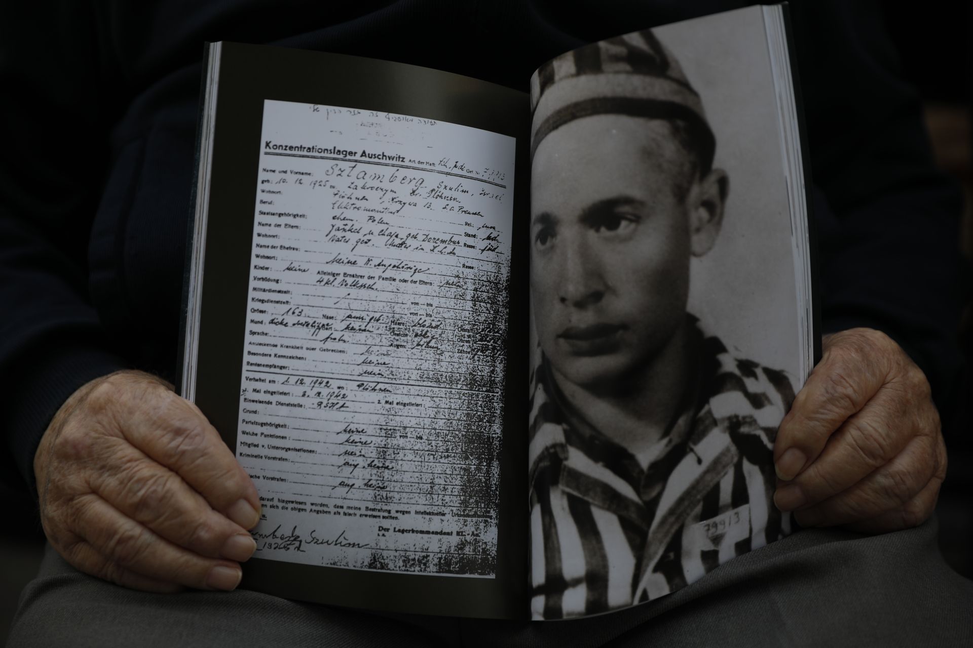 Шалом Стамберг, оцелял от Холокост, държи книга със снимка на себе си в ...