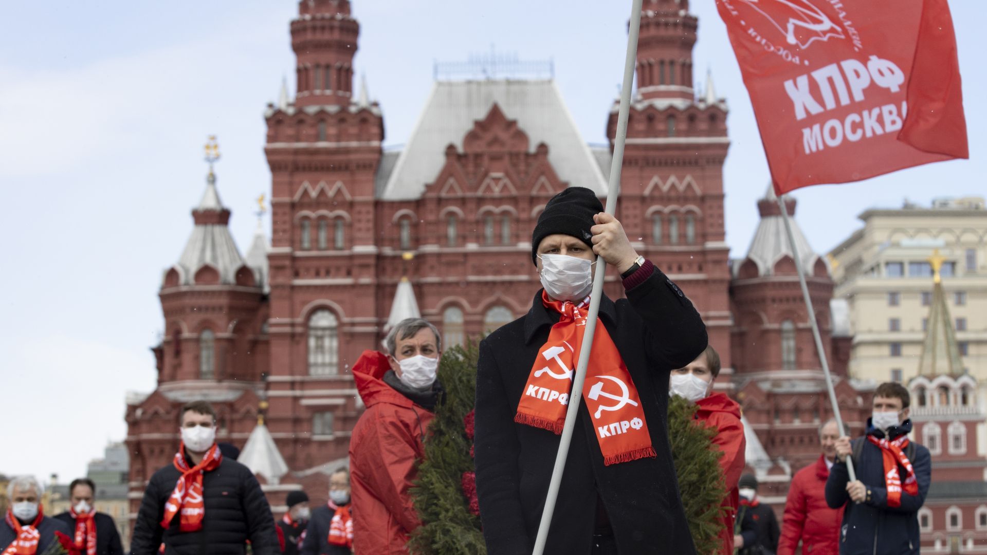 Малка група руски комунисти носещи защитни маски и червени знамена