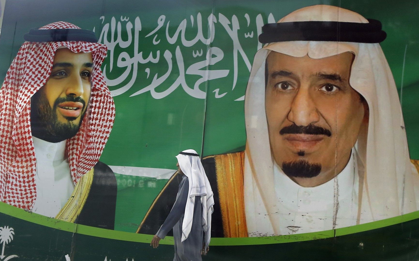 Мъж минава покрай плакат пред мол в Джида, Саудитска Арабия, на който са изобразени крал Салман (вдясно) и престолонаследника Мохамед бин Салман