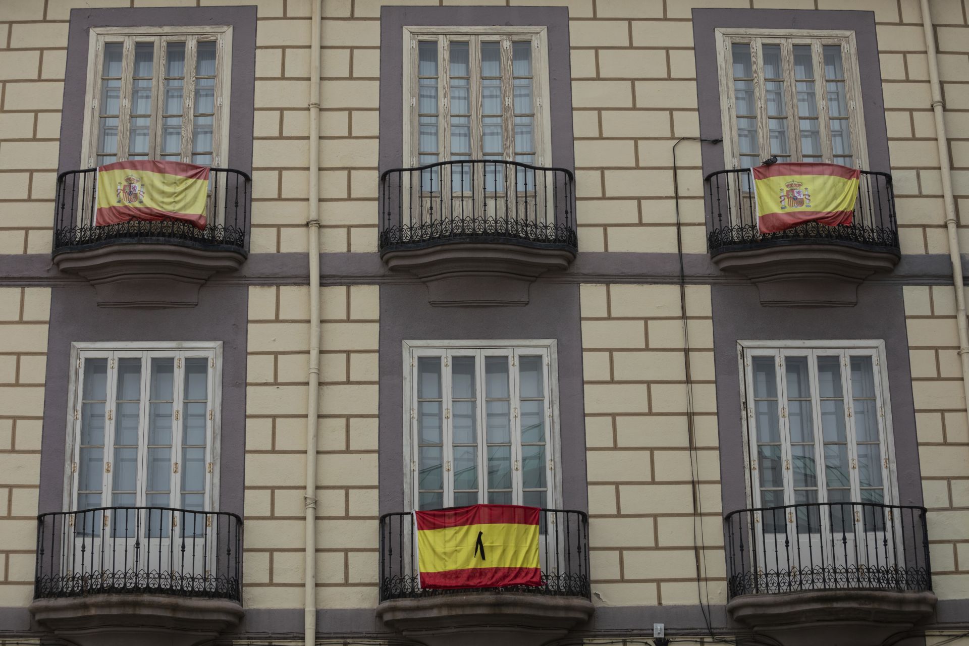 Испански флагове с черна панделка за жертвите на COVID-19, висят от фасадата на сграда в Мадрид