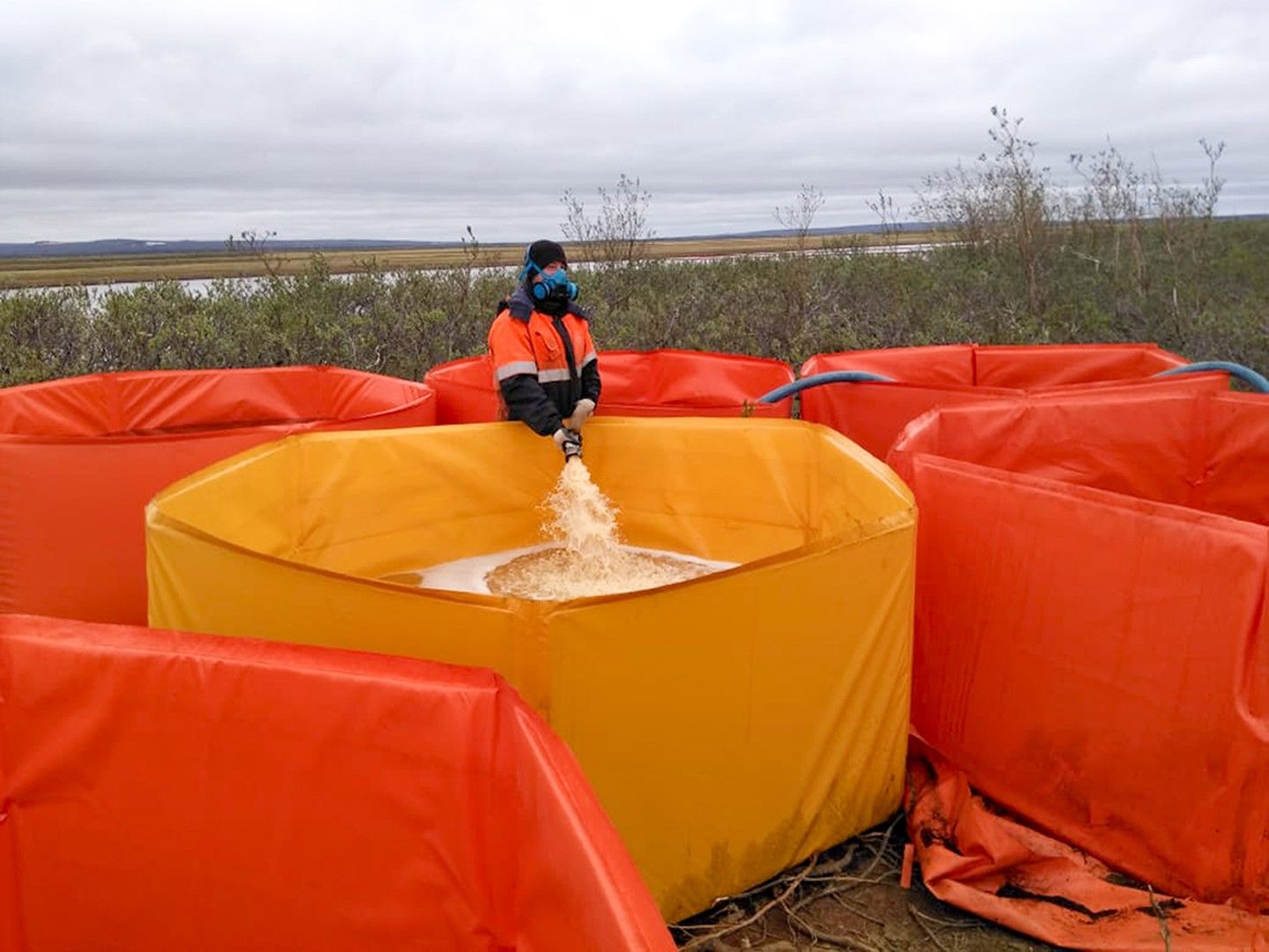 Служител на аварийните служби опитва да събере замърсена вода след разлива на горииво край Норилск
