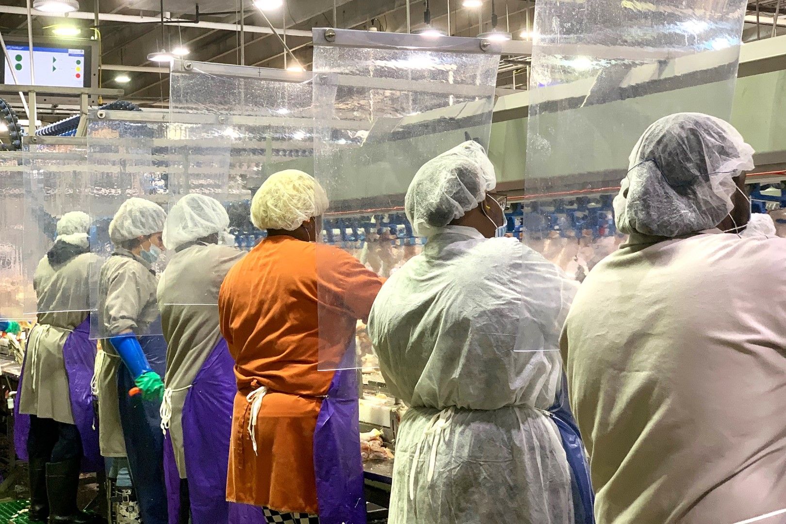Работниците в месокомбинат на компанията Тайсън (Tyson) носят маски и са зад пластмасови прегради