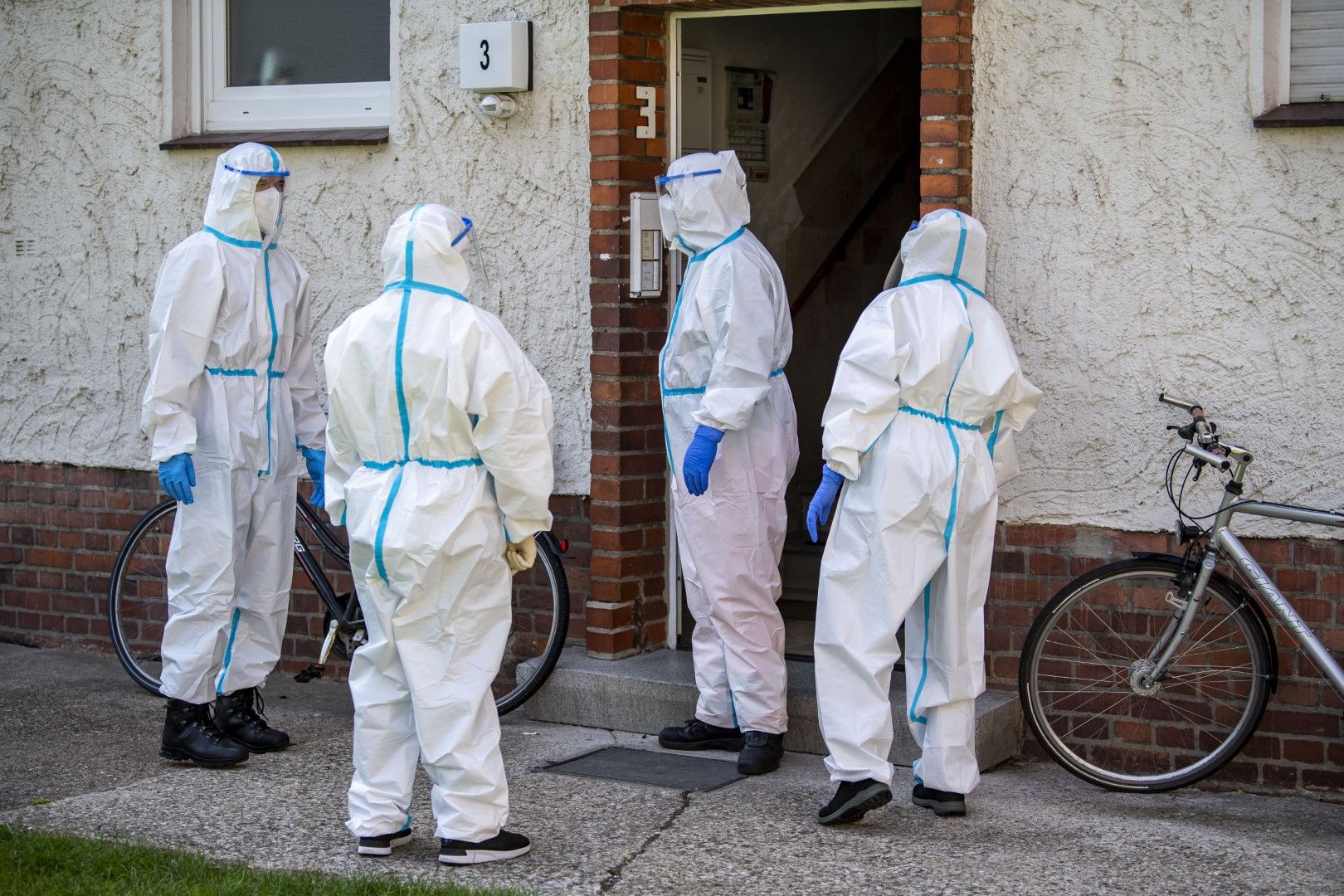 Здравни работници стоят пред къщата на работник от кланицата на концерна "Тьонис" в Германия, в която бяха разкрити стотици заразени с коронавирус