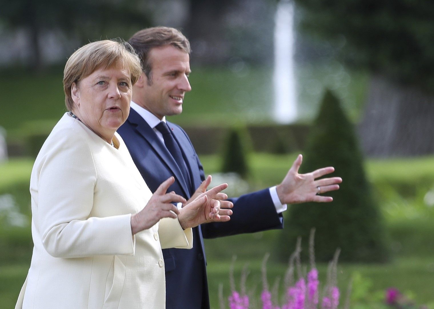 Германският канцлер Ангела Меркел и френският президент Еманюел Макрон жестикулират, докато се разхождат в резиденцията на германското правителство в замъка Месеберг в Гранзе, близо до Берлин, 29 юни