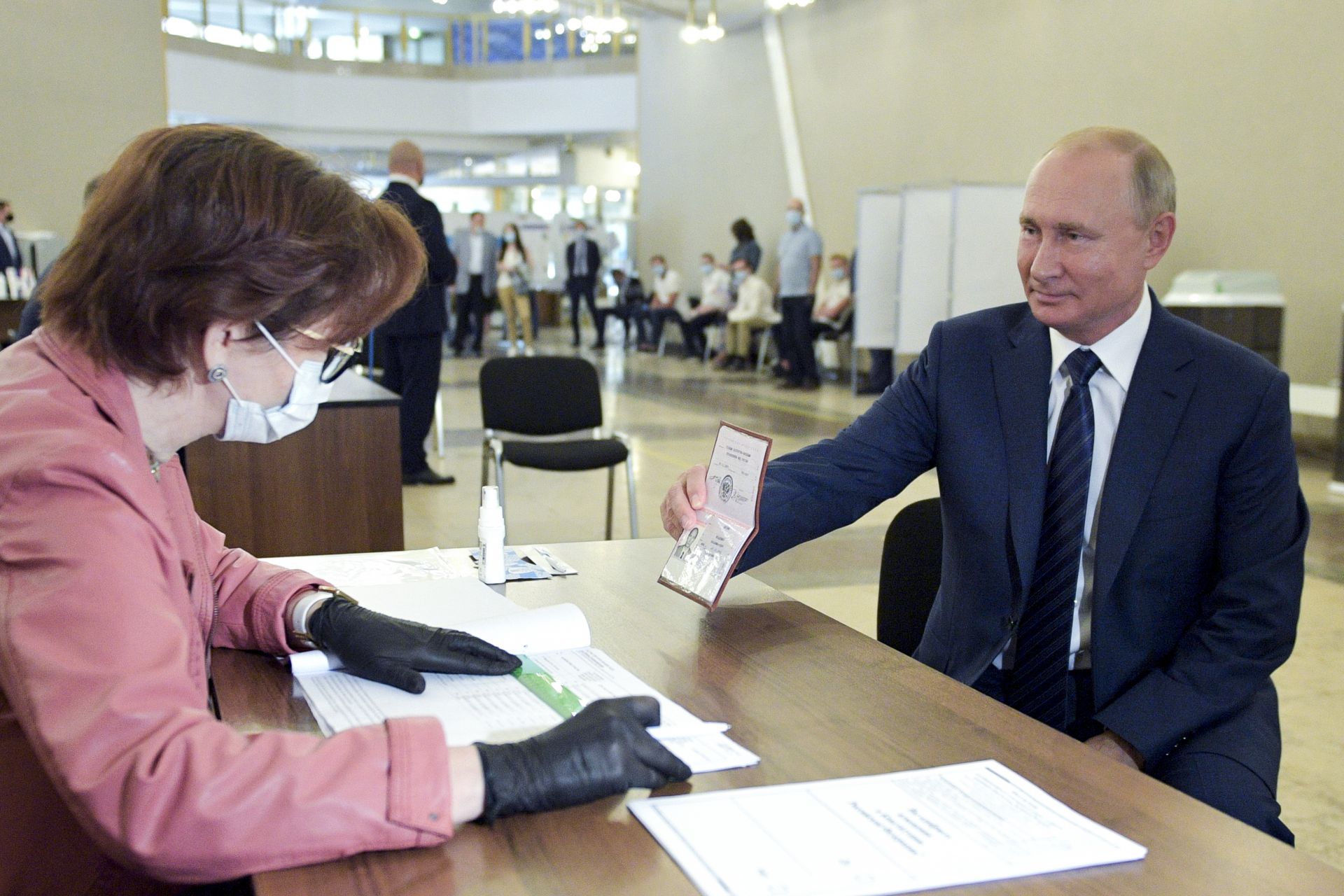 Путин показва паспорта си пред член на изборната комисия при упражняване на своя вот в Москва