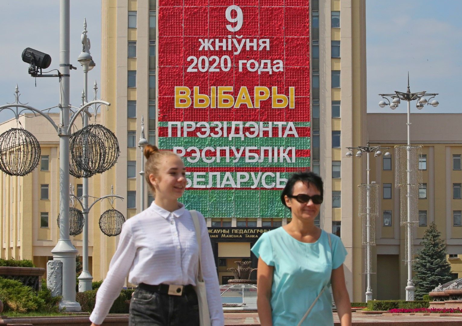 Беларус се готви за президентски избори на 9 август: две жени преминават под предизборен билборд в Минск
