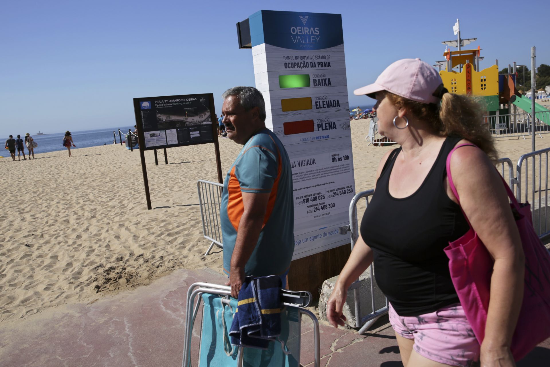 Хората, пристигащи на плаж в Лисабон, минават покрай семафорна система, която сигнализира колко е претъпкан плажът във всеки момент
