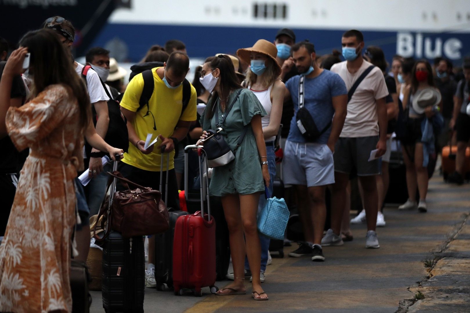Туристи с предпазни маски чакат да се каат на ферибото на пристанището в Пирея, недалеч от Атина, на 7 август