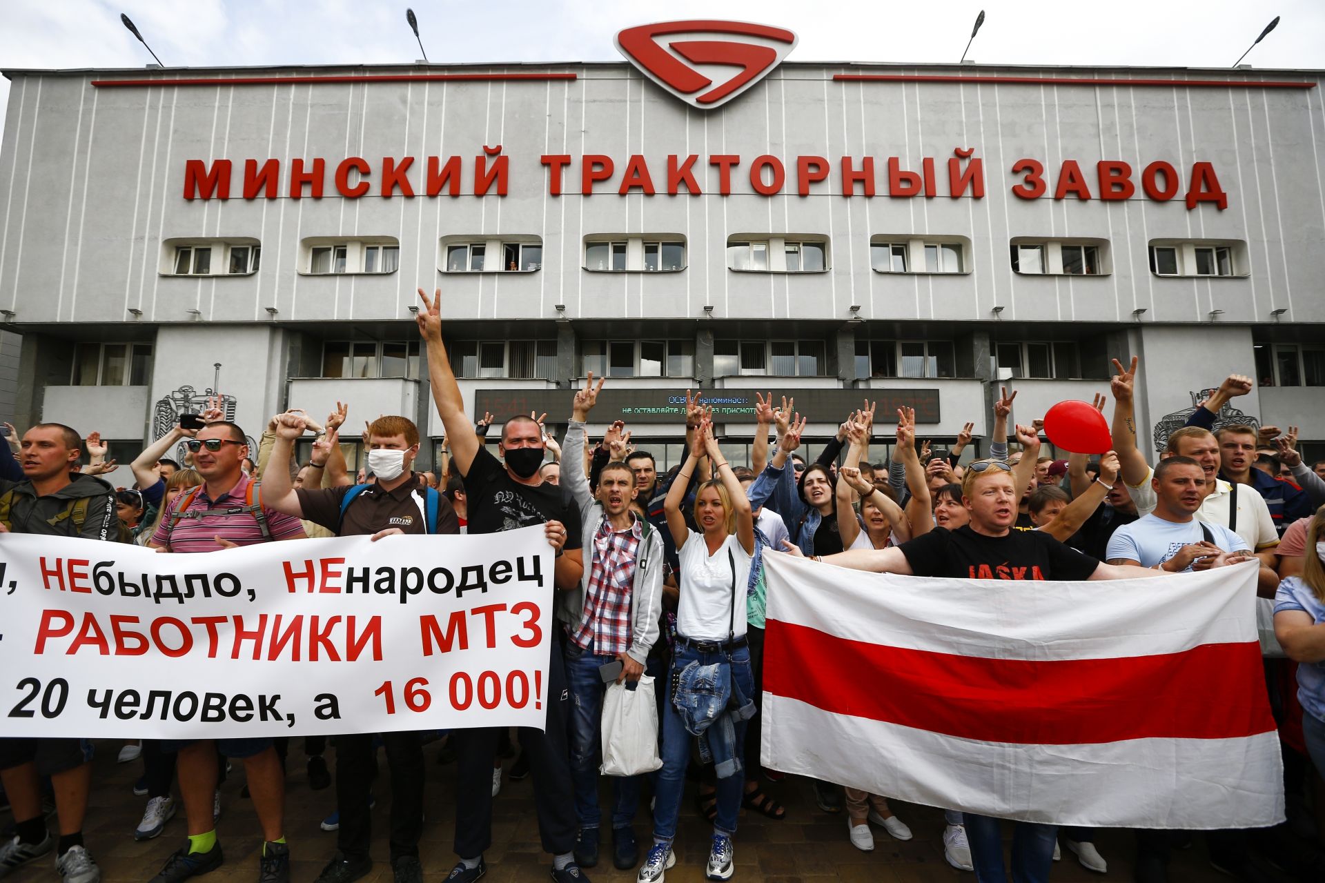 Работниците държат банер с надпис "ние не сме говеда, не сме овце, ние сме работници на МТЗ, не сме 20 души, ние сме 16 000", докато те маршират по време на митинг край Минския завод за трактори