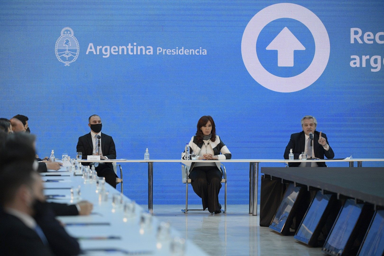 Вицепрезидентът на Аржентина Кристина Фернандес, в центъра, и министърът на икономиката Мартин Гусман, вляво, слушат как президентът Алберто Фернандес говори по време на церемония, обявяваща резултатите от преструктурирането на външния дълг