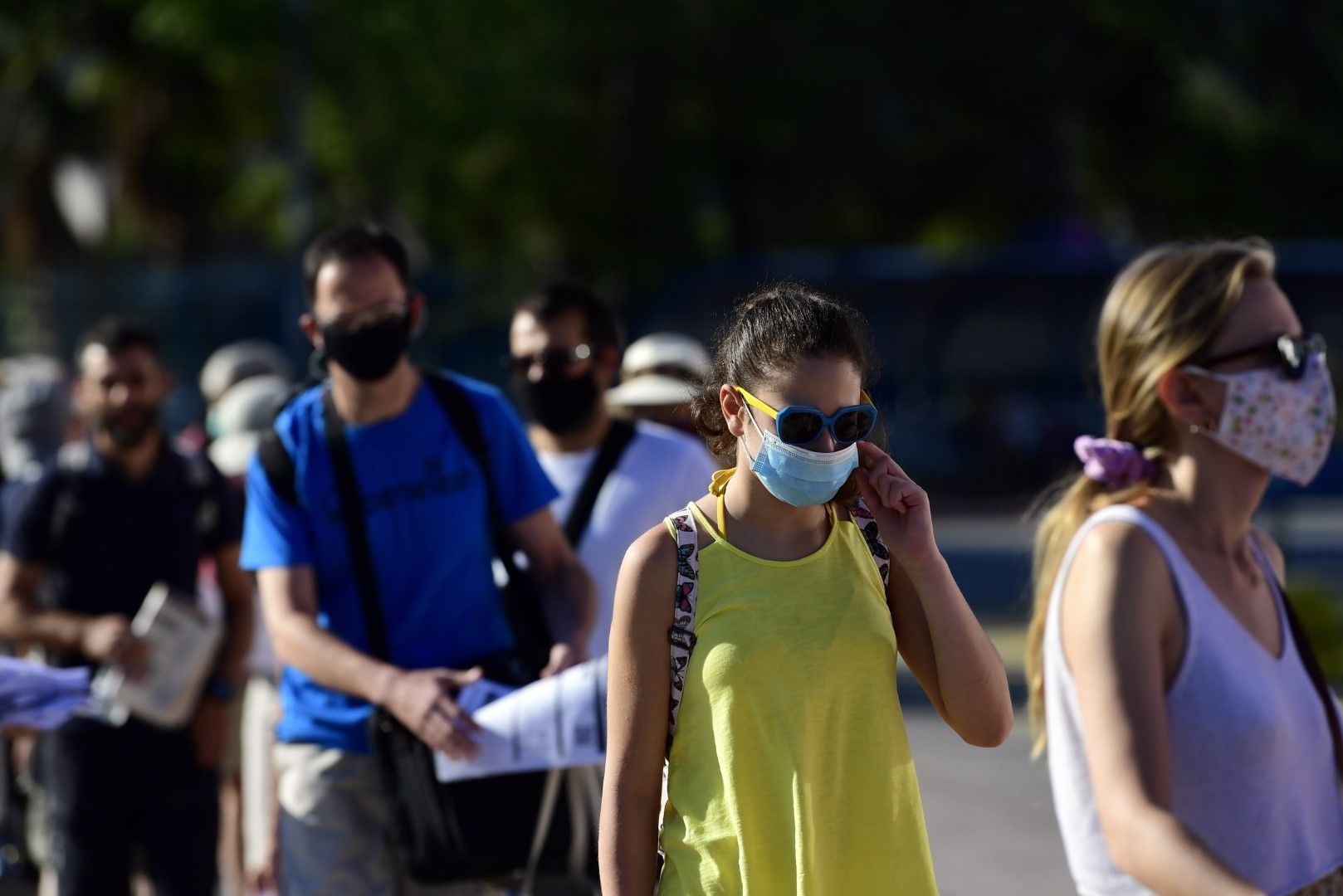 Туристи с предпазни маски чакат на опашка за ферибот на пристанището в Пирея, недалеч от Атина
