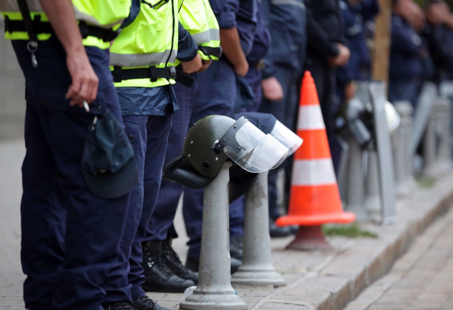 Полицаи със свалени каски стоят пред протестиращите