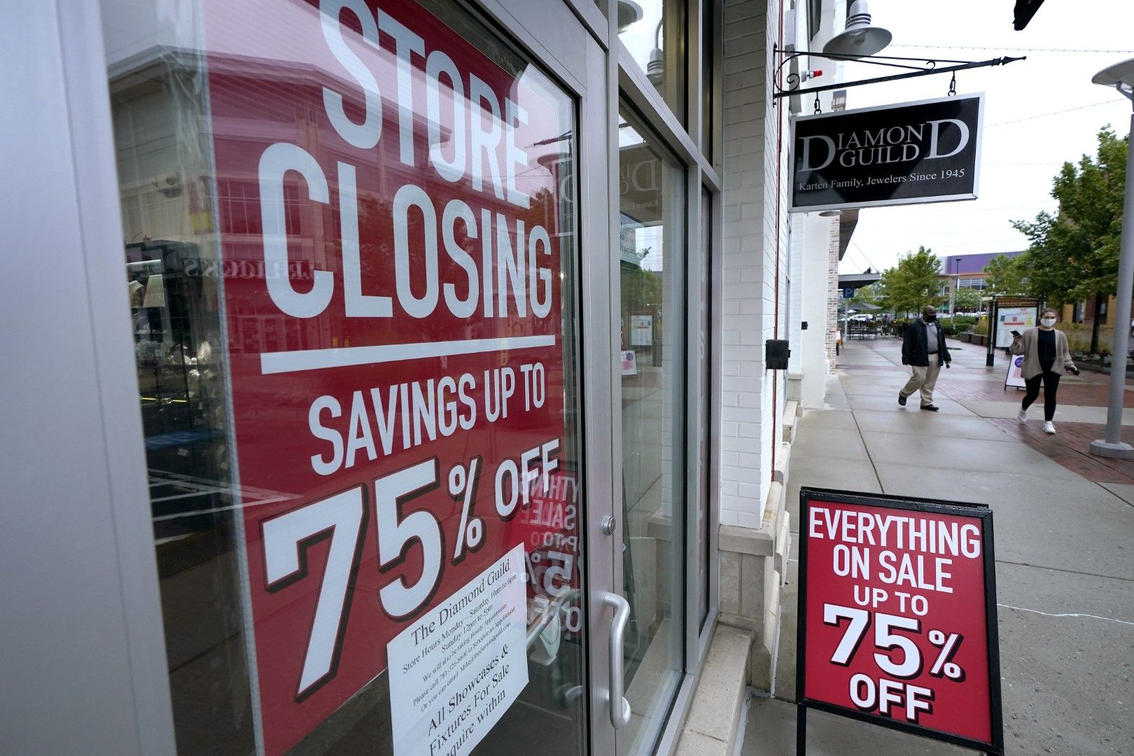 Пешеходци минават покрай витрина със знаци за затваряне на магазин и разпродажба в Дедъм, Масачузетс