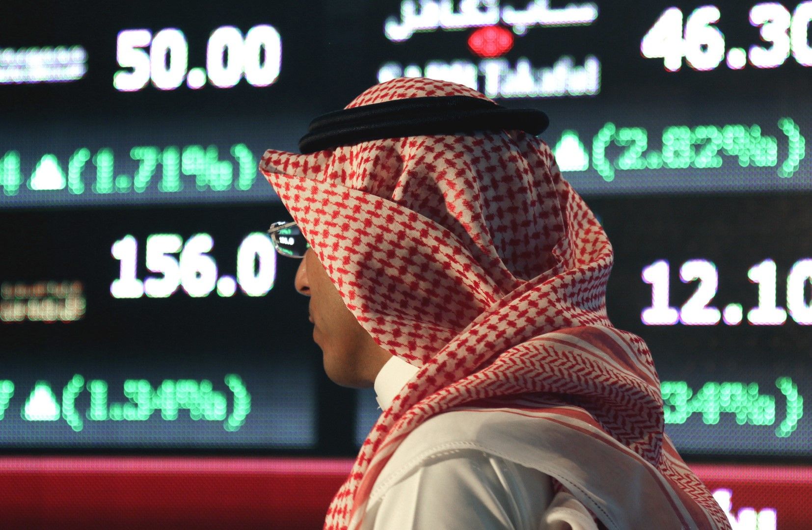 Саудитец минава покрай фондовата борса в Рияд. Сливането на банките трябва да получи одобрението на регулаторите в страната