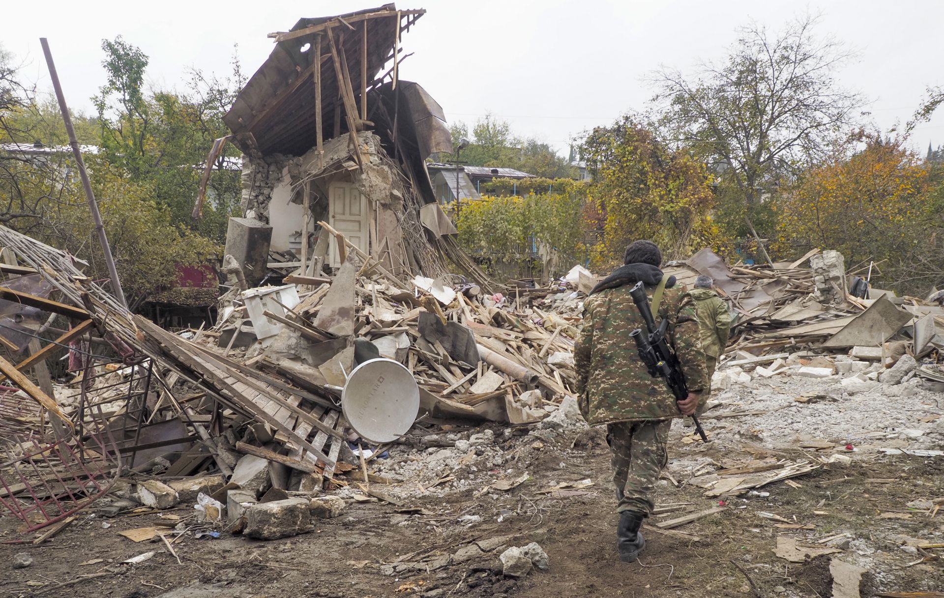 Етнически арменски войници минават покрай къща, разрушена от обстрела от азербайджанската артилерия в Степанакерт