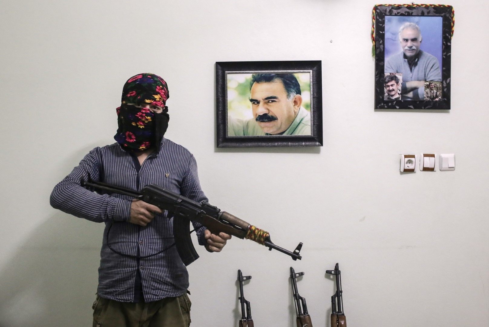 Боец на ПКК - Кюрдска работническа партия, на фона на портрета на лидера на партията Абдулах Йоджалан