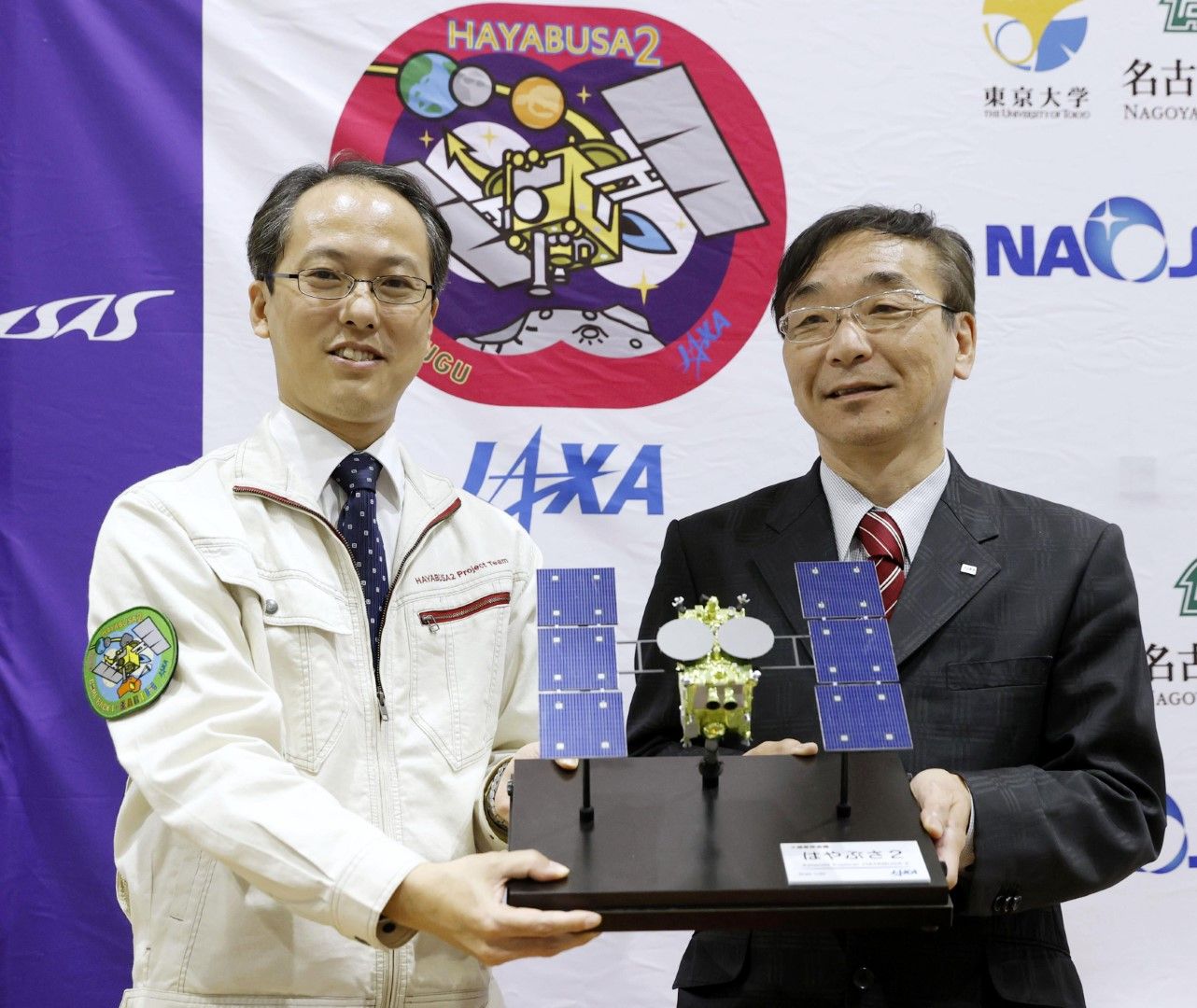 Юичи Цуда, вляво, ръководител на проекта Hayabusa2 на Японската агенция за аерокосмически изследвания (JAXA) и Хитоши Кунинака, генерален директор позират с модел на сондата по време на пресконференция в неделя, 6 декември