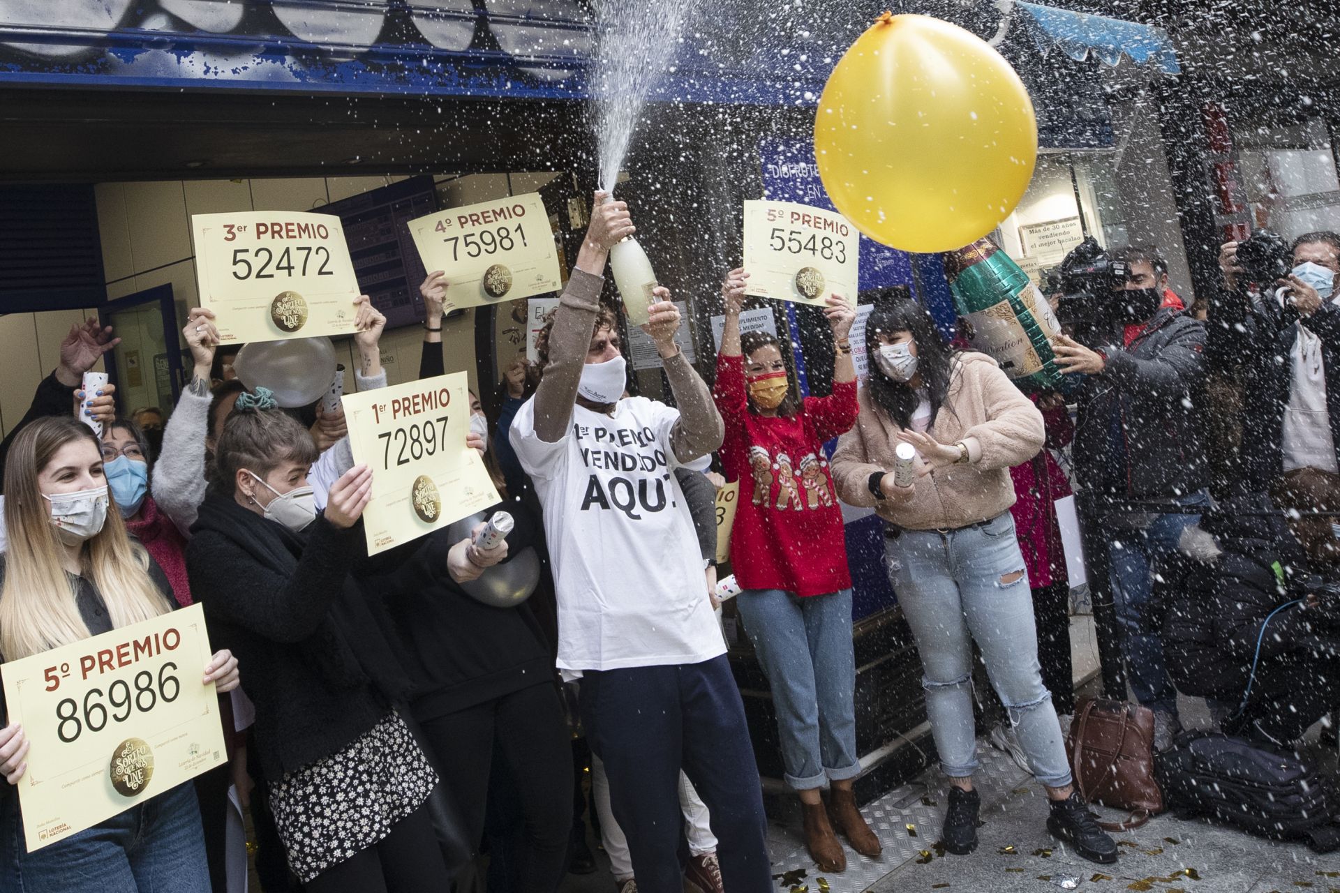 Работници от билетната каса на Dona Manolita празнуват мястото, където бяха продадени печелившите билети на коледната лотария на страната