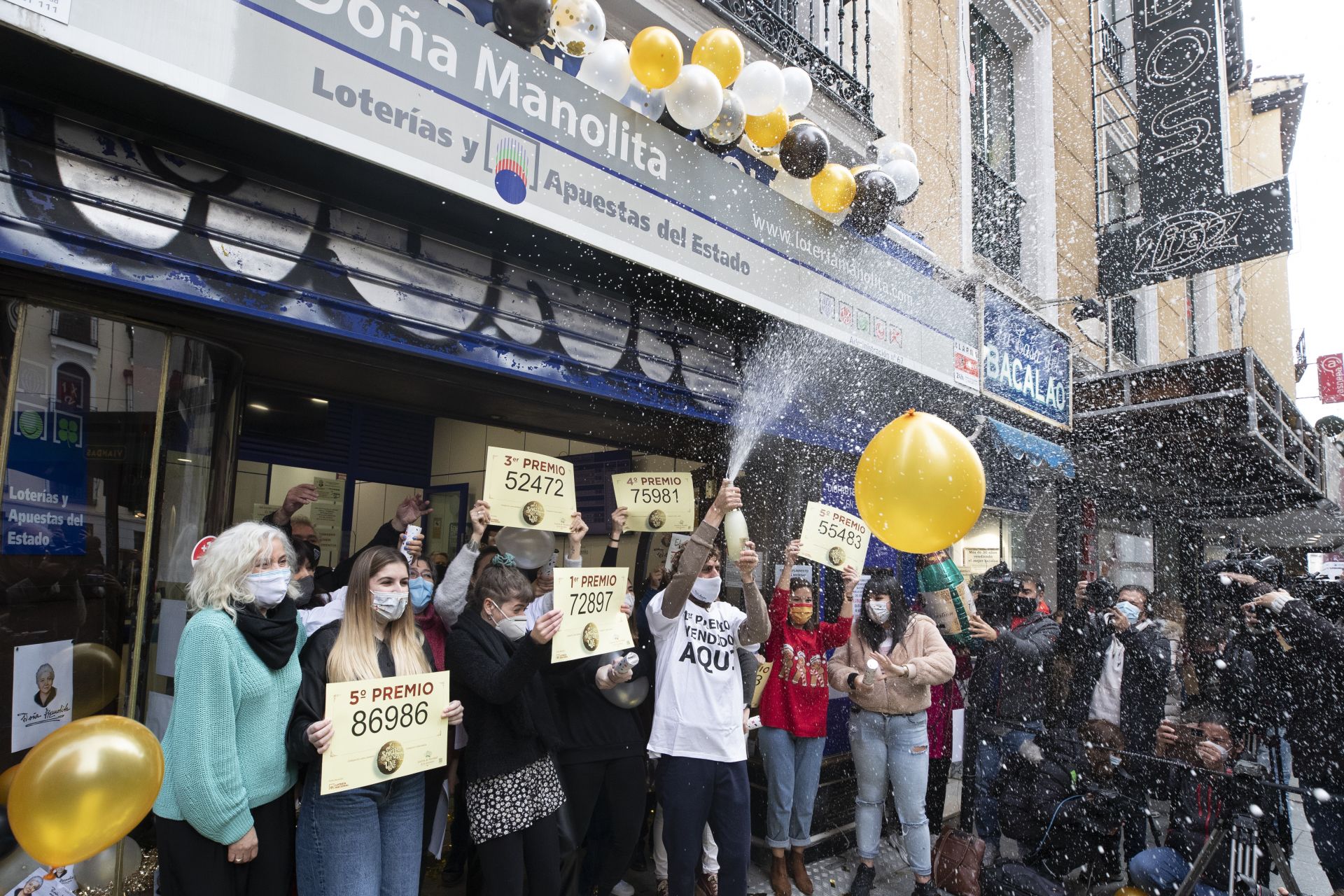 Работници от билетната каса на Dona Manolita празнуват мястото, където бяха продадени печелившите билети на коледната лотария на страната