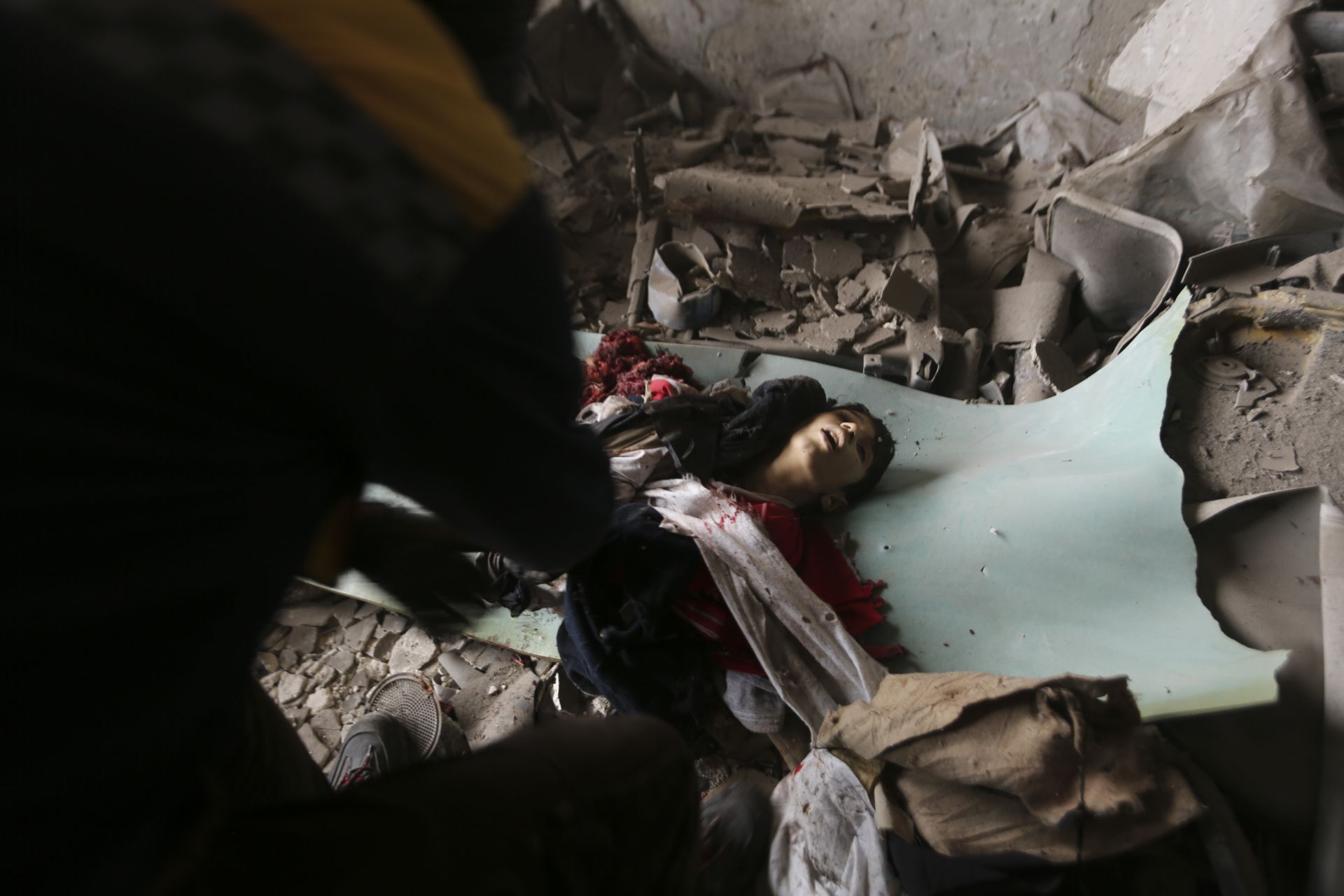 Военни събират тялото на момче, убито при въздушен удар в град Идлиб, Сирия. (11 февруари 2020 г.)