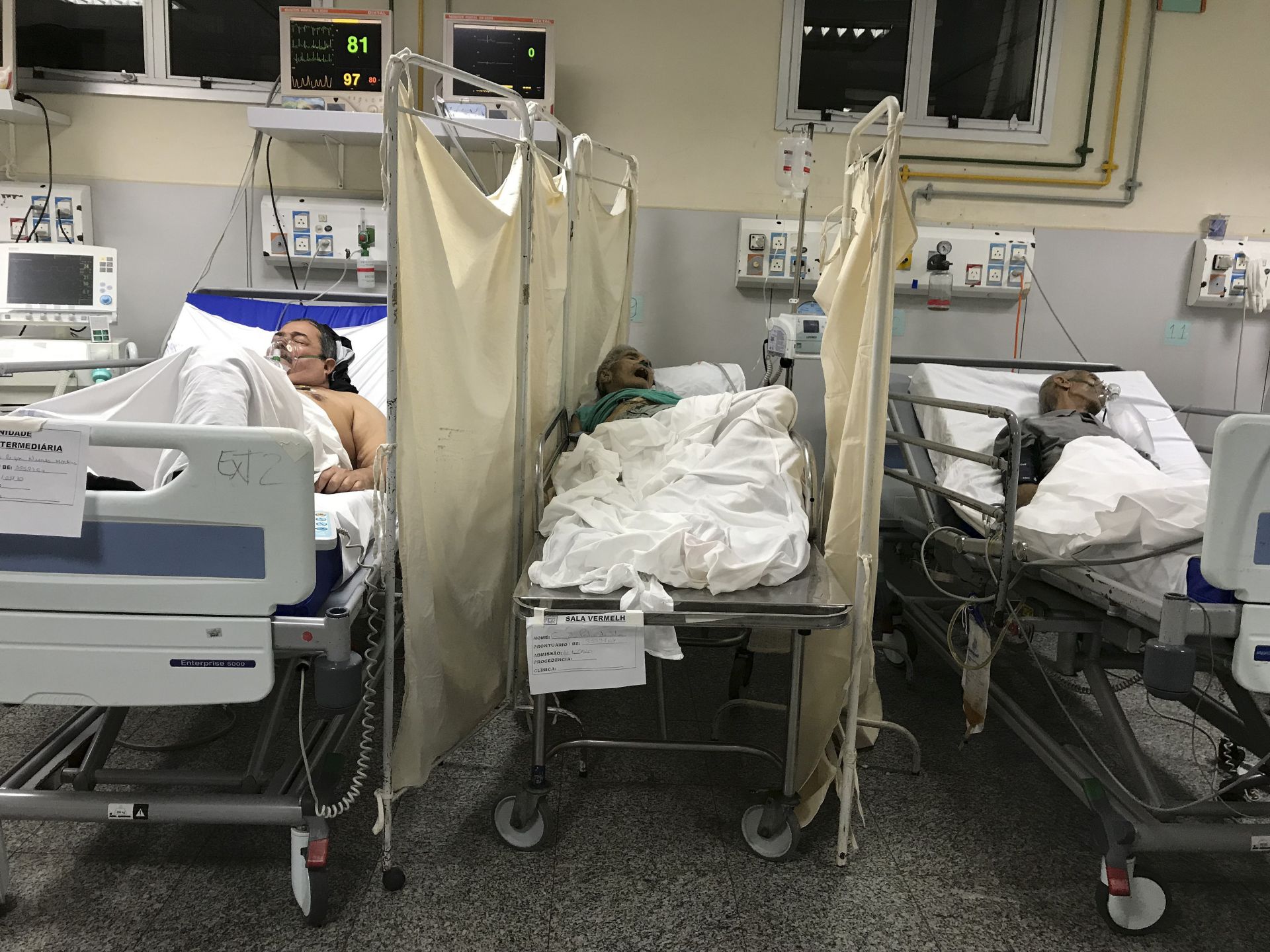 Починал от COVID-19 лежи на легло между двама други пациенти, заразени с коронавирус, в общинската болница в Рио де Жанейро, Бразилия. (24 май 2020 г.)