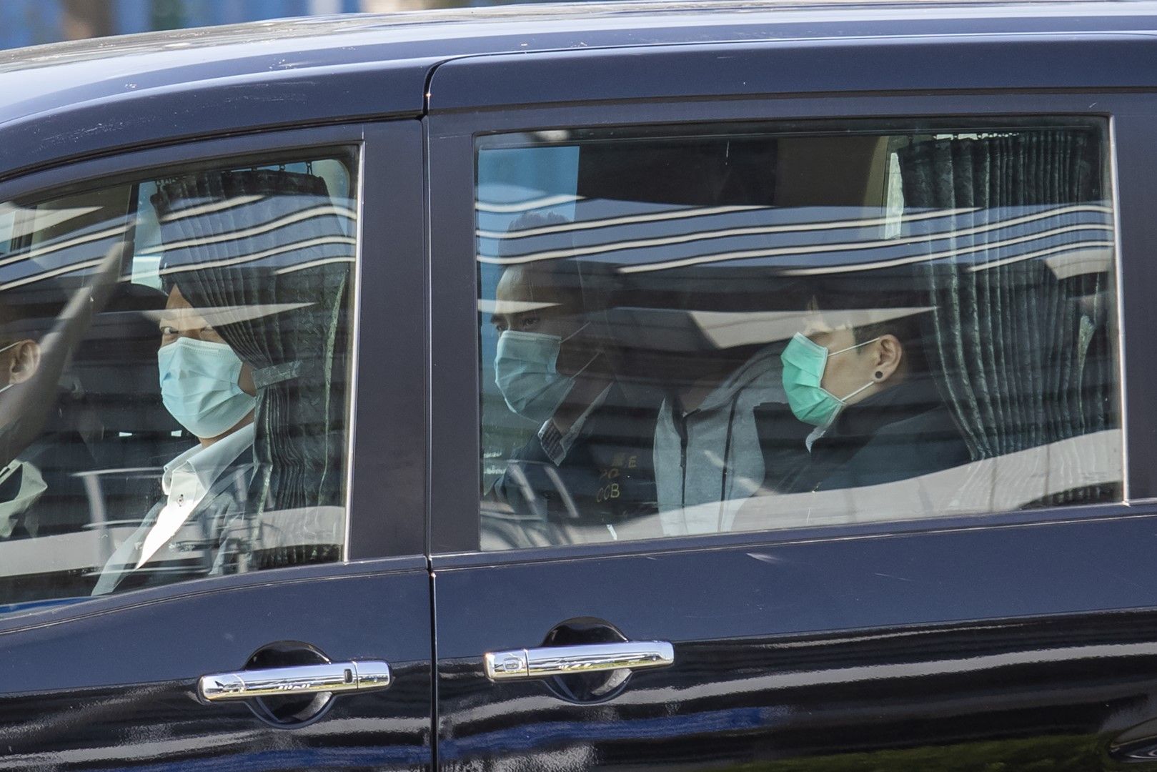 В колата на задната седалка с покрита глава е един от осъдените активисти от Хонконг