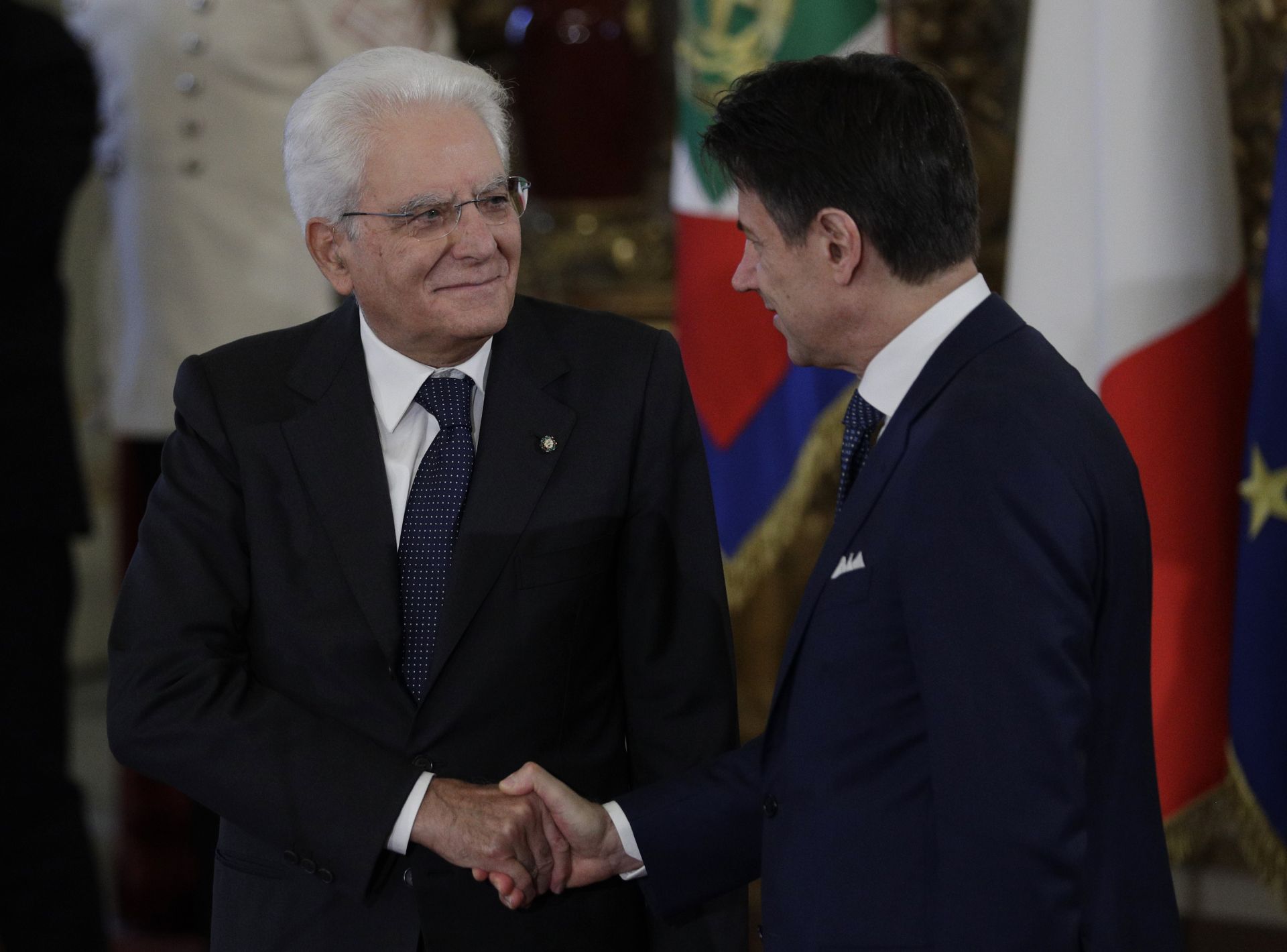 На тази снимка от 5 септември 2019 г., италианският президент Серджо Матарела, вляво, се ръкува с премиера Джузепе Конте по време на церемонията по полагане на клетва в президентския дворец