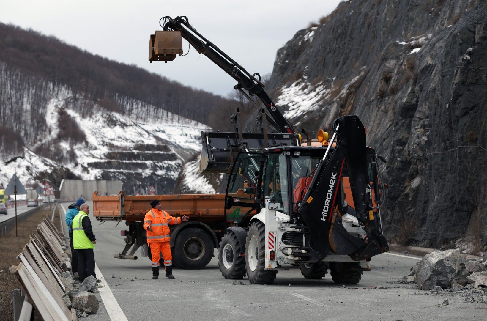 Работници от поддържаща фирма и от Областно пътно управление почистват и извозват срутена скална маса в района на срутището при 8-и км на АМ "Струма", 31 януари 2021 г.