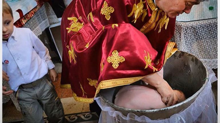 Свещеникът потапя бебето изцяло в купела - цели три пъти.