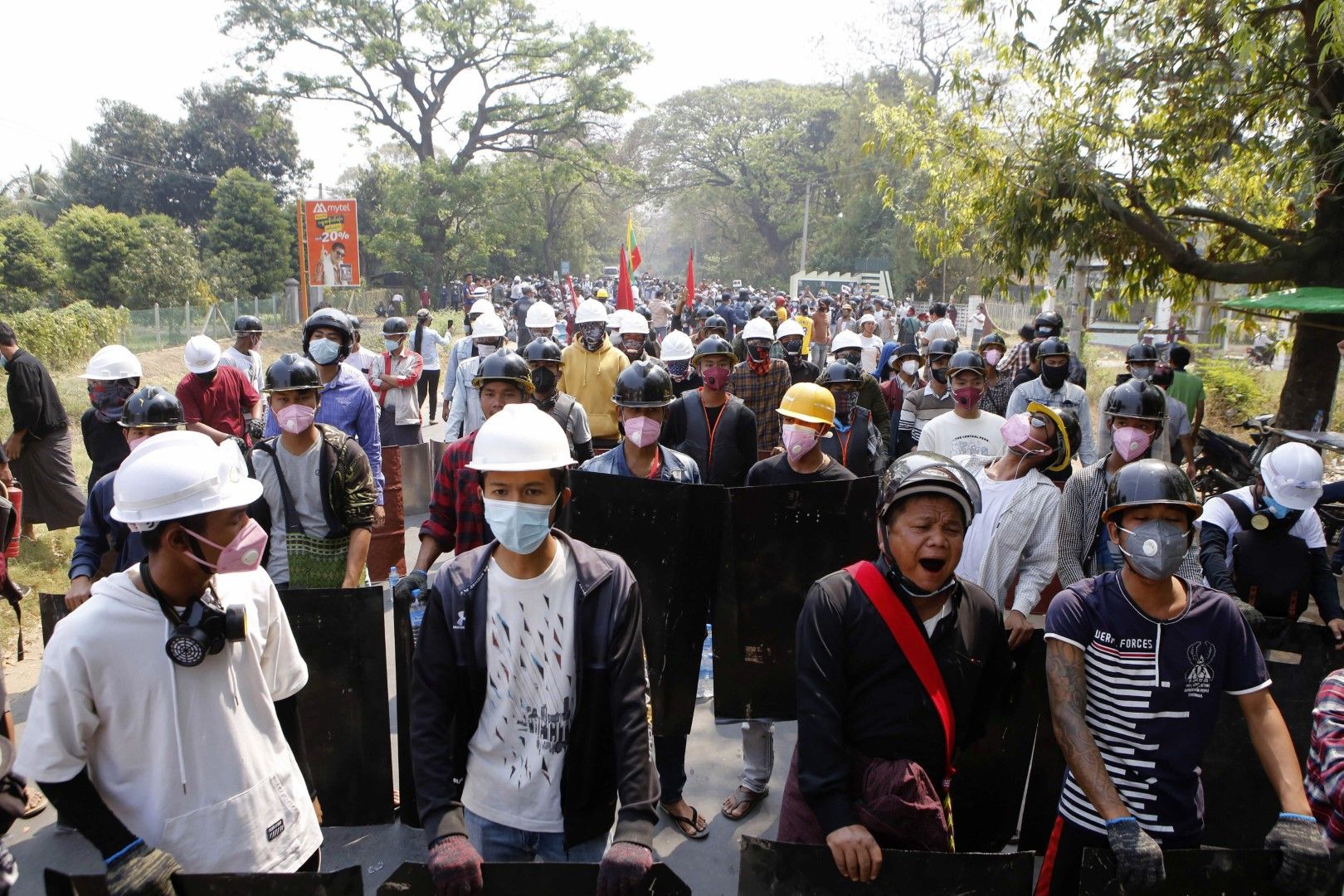 Протестиращи стоят зад импровизирана барикада, докато полицията се готви да стреля със сълзотворен газ в Найпйитау, Мианмар, на 8 март