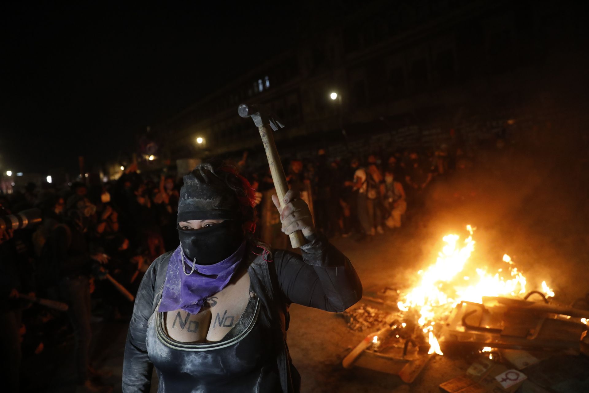  Демонстрант размахва чук като възпламенява огън пред Националния замък по време на марш за отбелязване на Международния ден на дамите и митинг против насилието сред половете в Мексико 