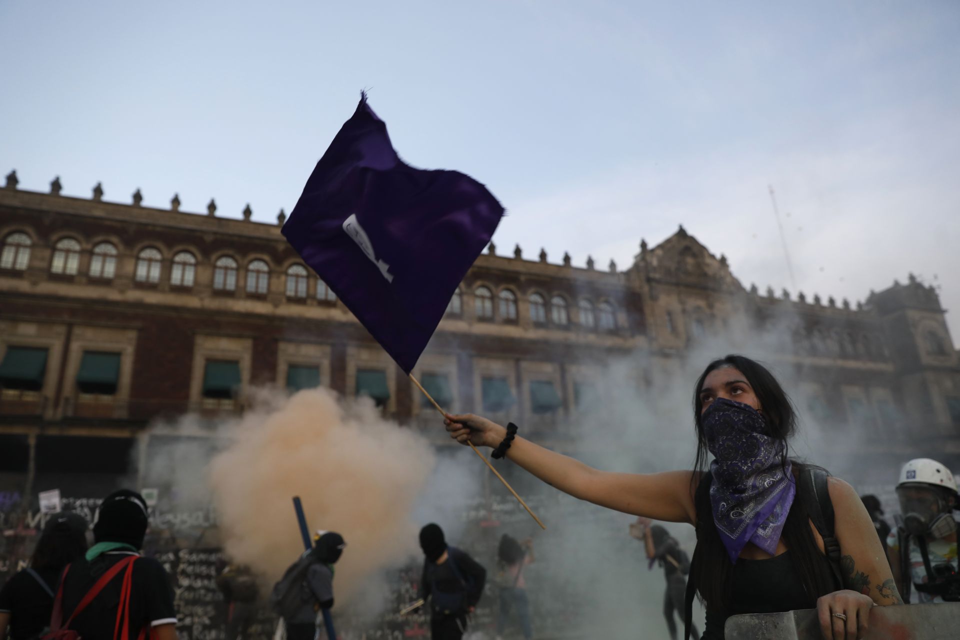Жена развява феминистко знаме, докато демонстранти се опитват да щурмуват Националния дворец