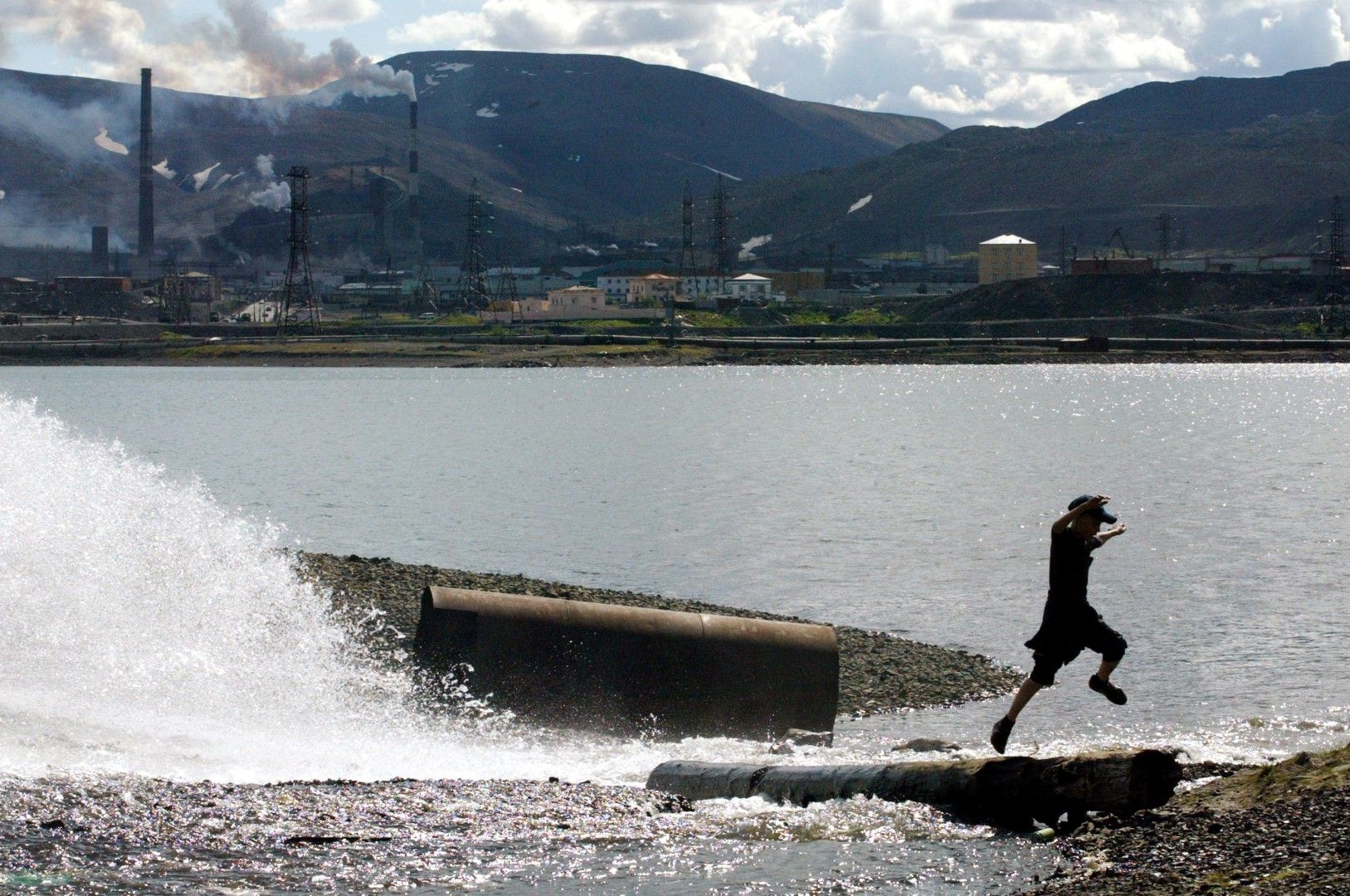 Момче скача в изкуствено езеро на 18 юли 2002 г. в Норилск, Русия. На заден план завод за никел. Водата се използва за охлаждане в никеловите рафинерии
