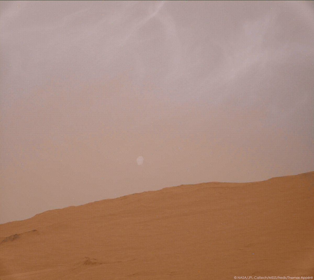 Фобос изгрява, на фона на рехеста облачност на Марс