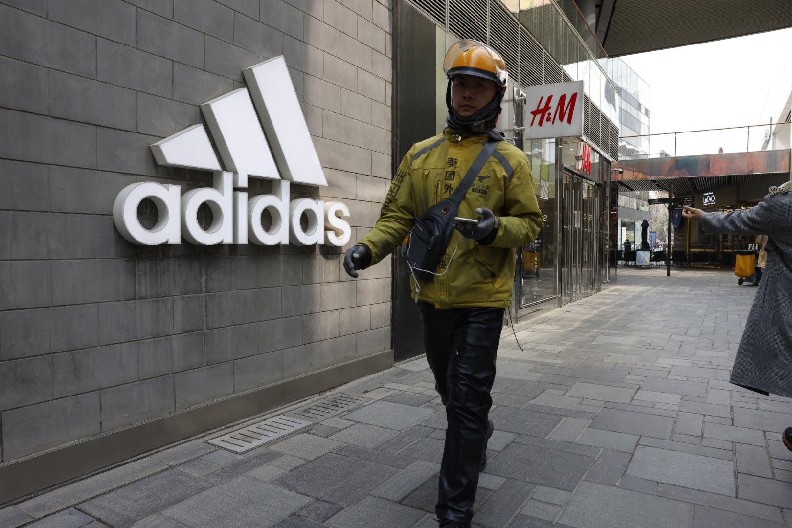 Пешеходци минават покрай магазини на Adidas и Nike на централна улица в Пекин, 25 март