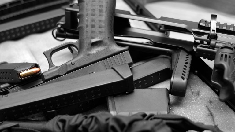 Млад мъж с шест огнестрелни оръжия, включително автомат и пушка,