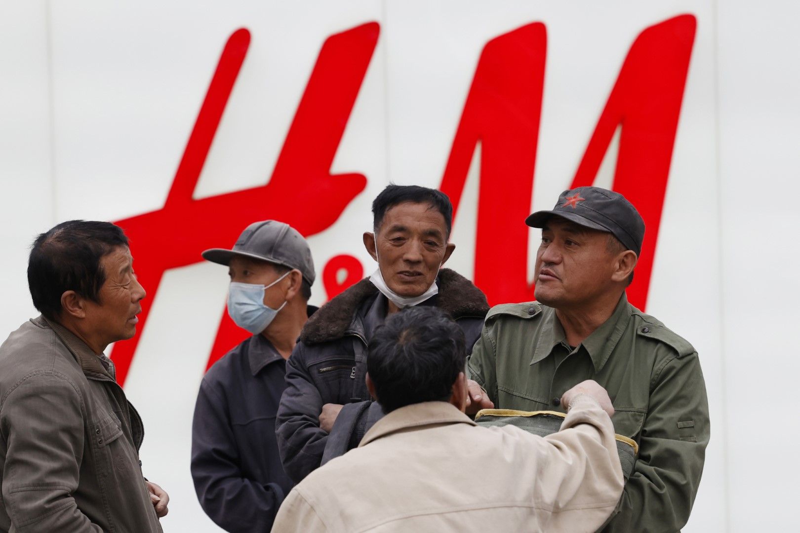 Работници мигранти се събират пред витрина на H&M в Пекин, 29 март 2021 г.