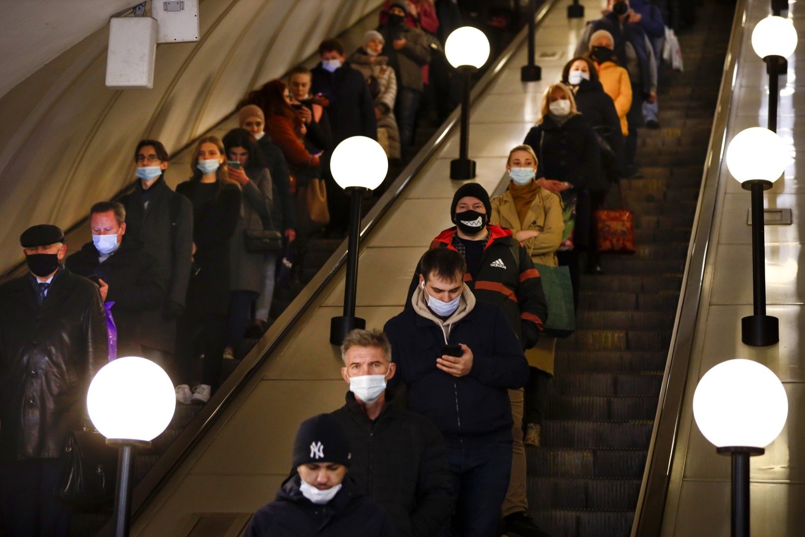 Хора с предпазни маски по ескалатора на метрото в Москва