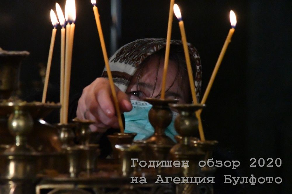  Жена с маска пали свещ по време на богослужението в столичния храм 