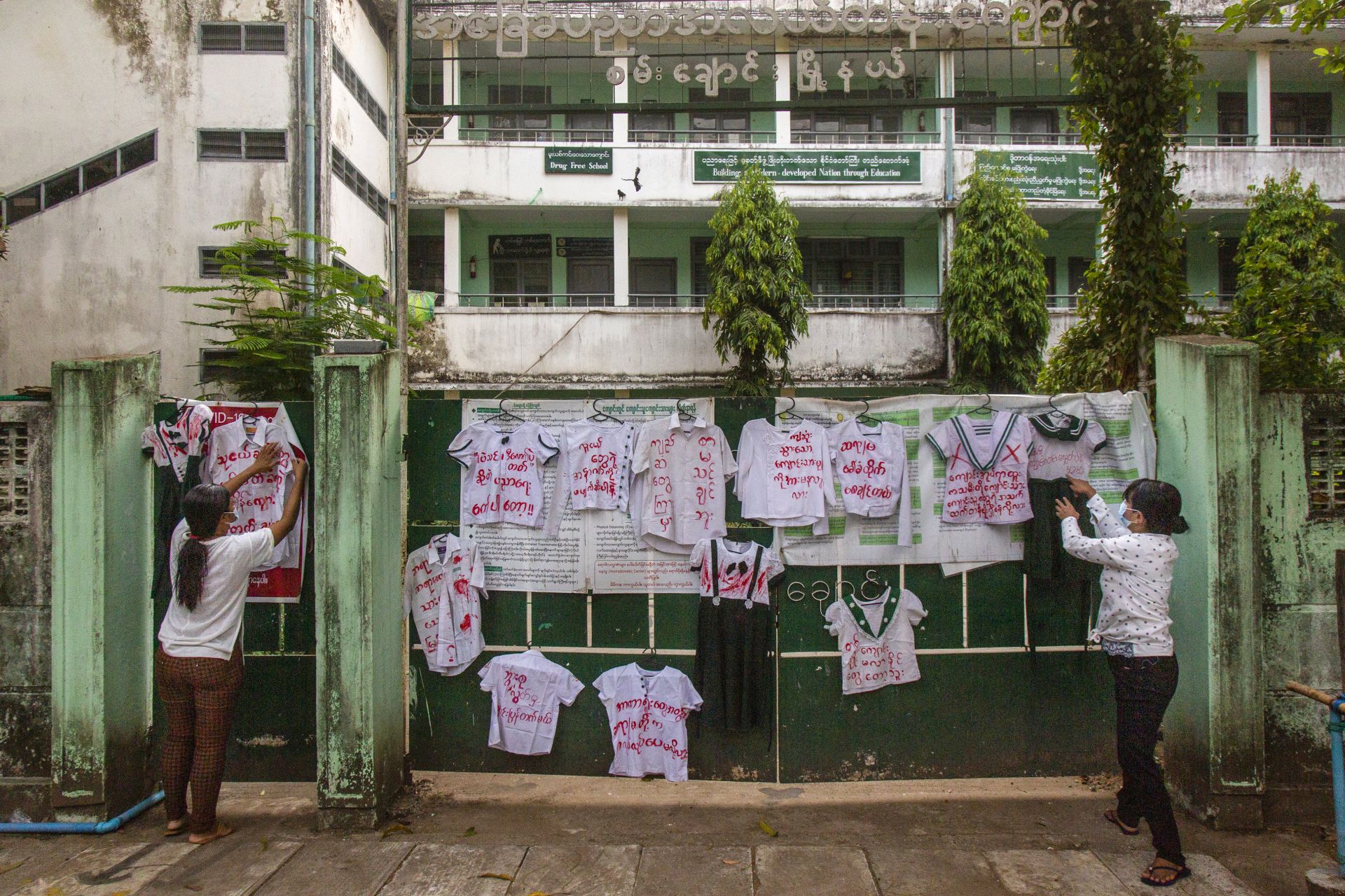 Активисти и протестиращи срещу преврата закачат ученически униформи на стената на училище по време на демонстрация