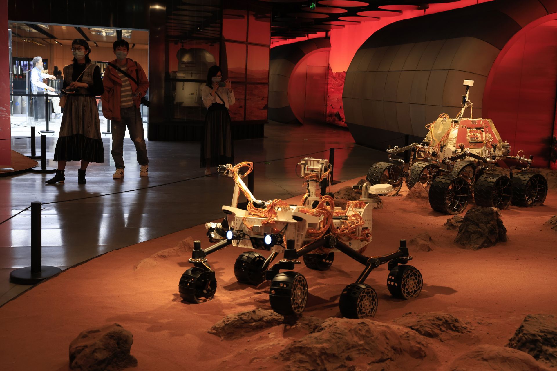 Посетителите минават покрай изложба с изображения на марсоходи на Марс в Пекин в петък, 14 май 