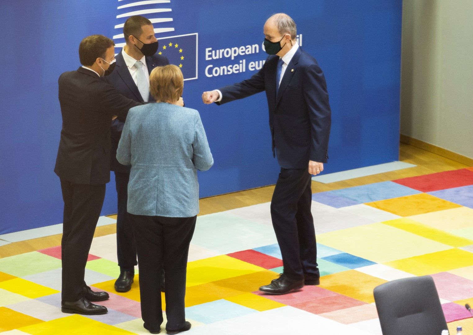 В юмручен поздрав на срещата на върха на ЕС в Брюксел - премиерът на Ирландия Майкъл Мартин (вдясно), френският президент Еманюел Макрон (вляво) и канцлерът на Германия Ангела Меркел. Мартин ще стои от едната страна на барикадата при споровете за данъка