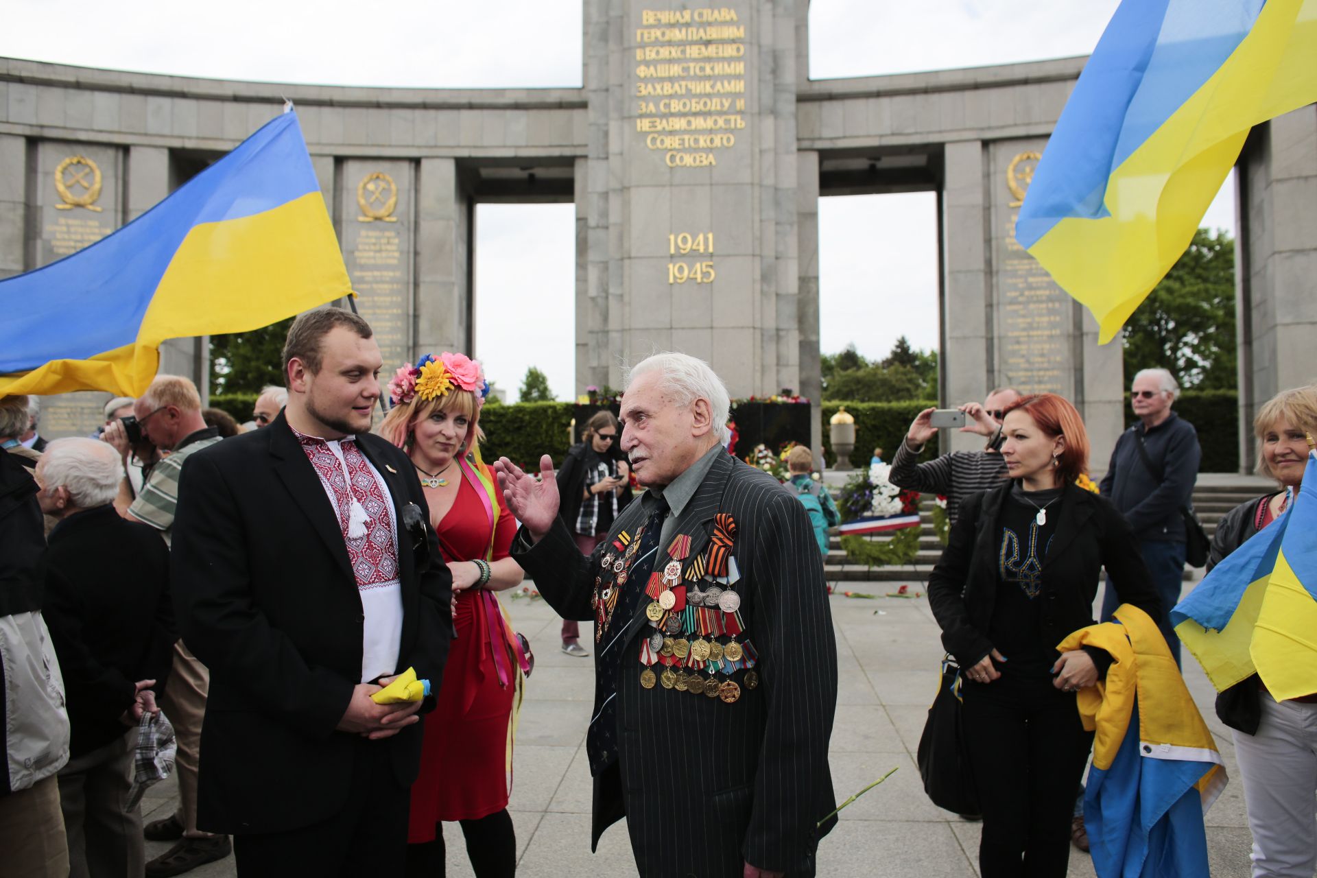 8 май 2015 г.: Дейвид Душман, 92 г., в центъра, говори на хора, държащи украински знамена, докато присъства на церемонията по поднасяне на венци в руския военен мемориал в берлинския квартал Тиргартен