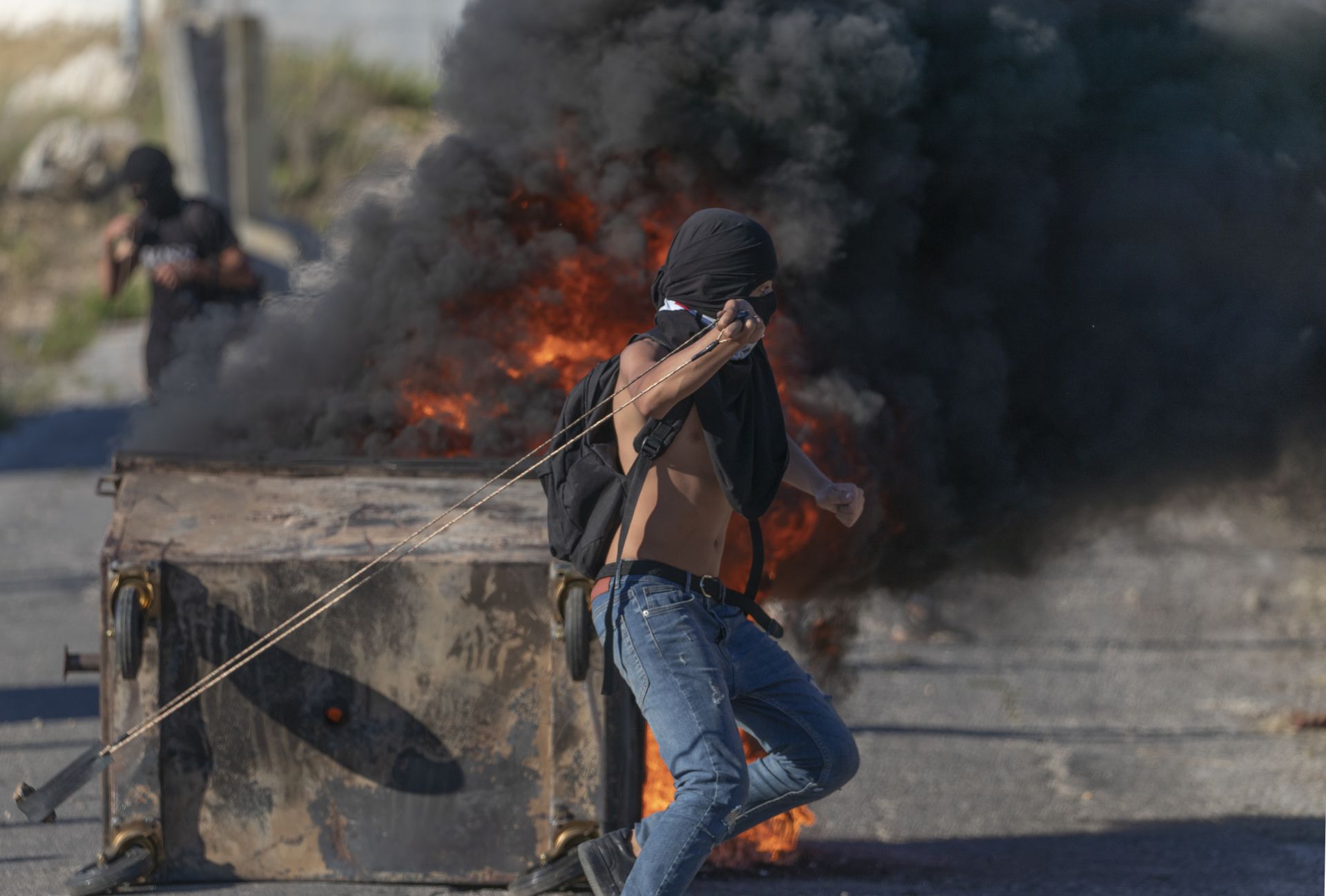 Палестински протестиращи горят гуми и използват подръчни средства за бой при сблъсъци с израелски войници на входа на еврейското селище Бейт Ел, близо до град Рамала на Западния бряг, 15 юни 2021