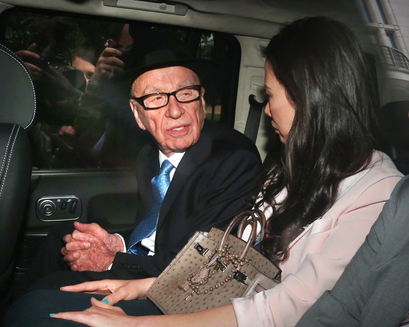 Рупърт Мърдок гледа към съпругата си Уенди Денг Мърдок в автомобила им, след като той даде показания в Кралския съд на 26 април 2012 г. Разследването се ръководи от лорд Джъстис Левсън и разглежда културата, практиката и етиката на пресата в Обединеното кралство