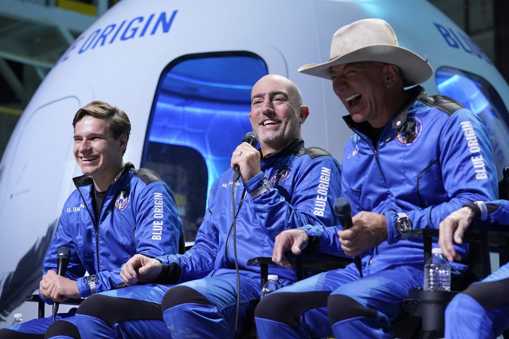 Оливър Дамен (вляво) и Джеф Безос (вдясно) се смеят, докато Марк Безос (в средата) прави коментари след тестовия опит на кораба на Блу Ориджин от космодрума край Ван Хорн, Тексас, вторник, 20 юли 2021 г. 